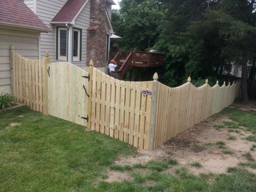6′ Board on Board with Dip & Gothic Posts A fence encloses the yard, and a wooden gate stands in the foreground.