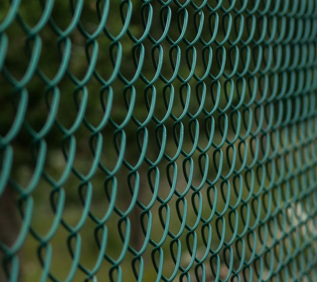 colored-fence A mesh of wire fencing and chain-link fencing creates a patterned fence outdoors.