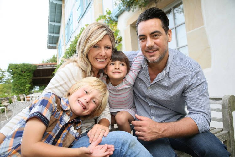 Family of four sitting in front of house Family of four sitting in front of house